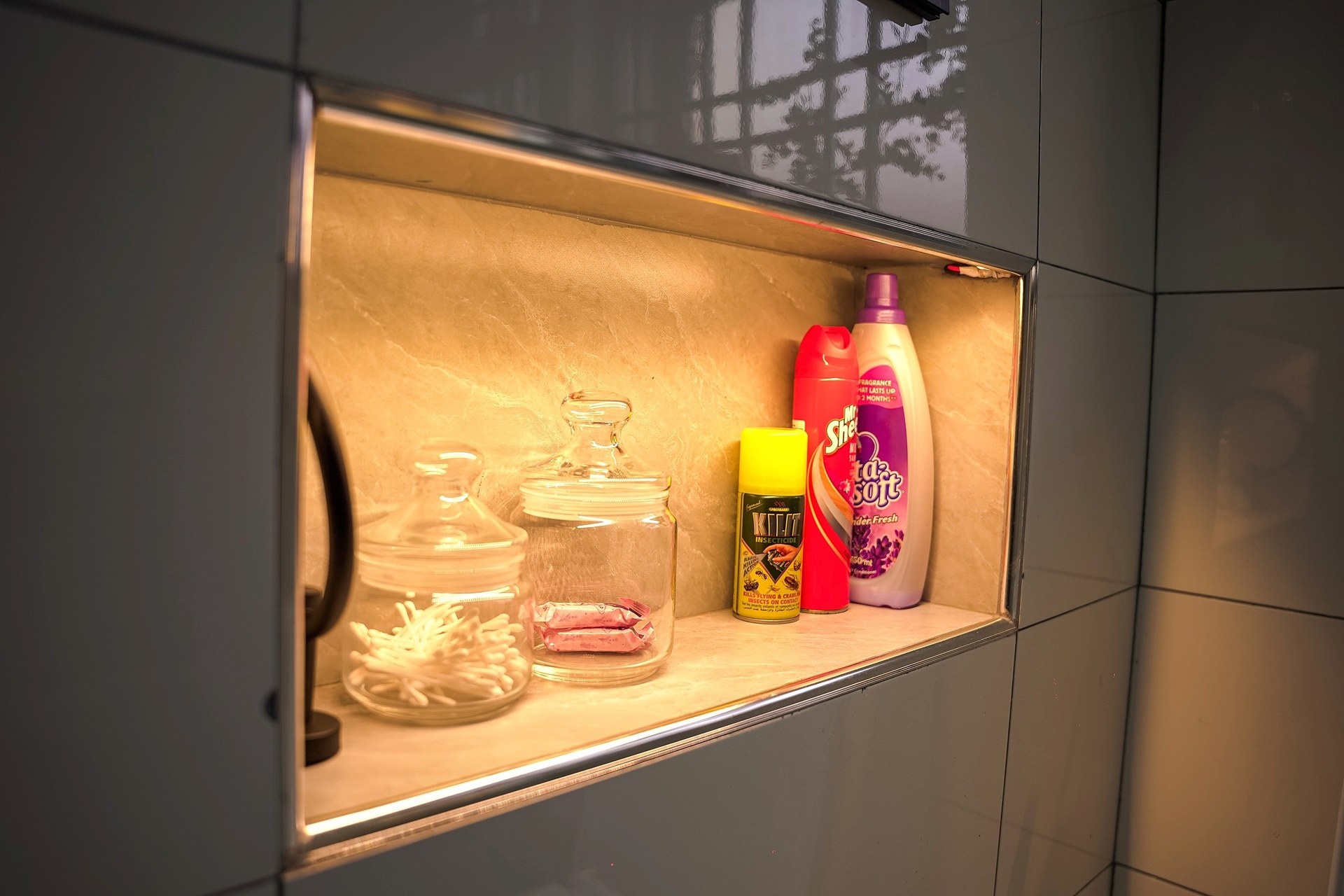 A shelf niche in the shower wall, lit warm from within