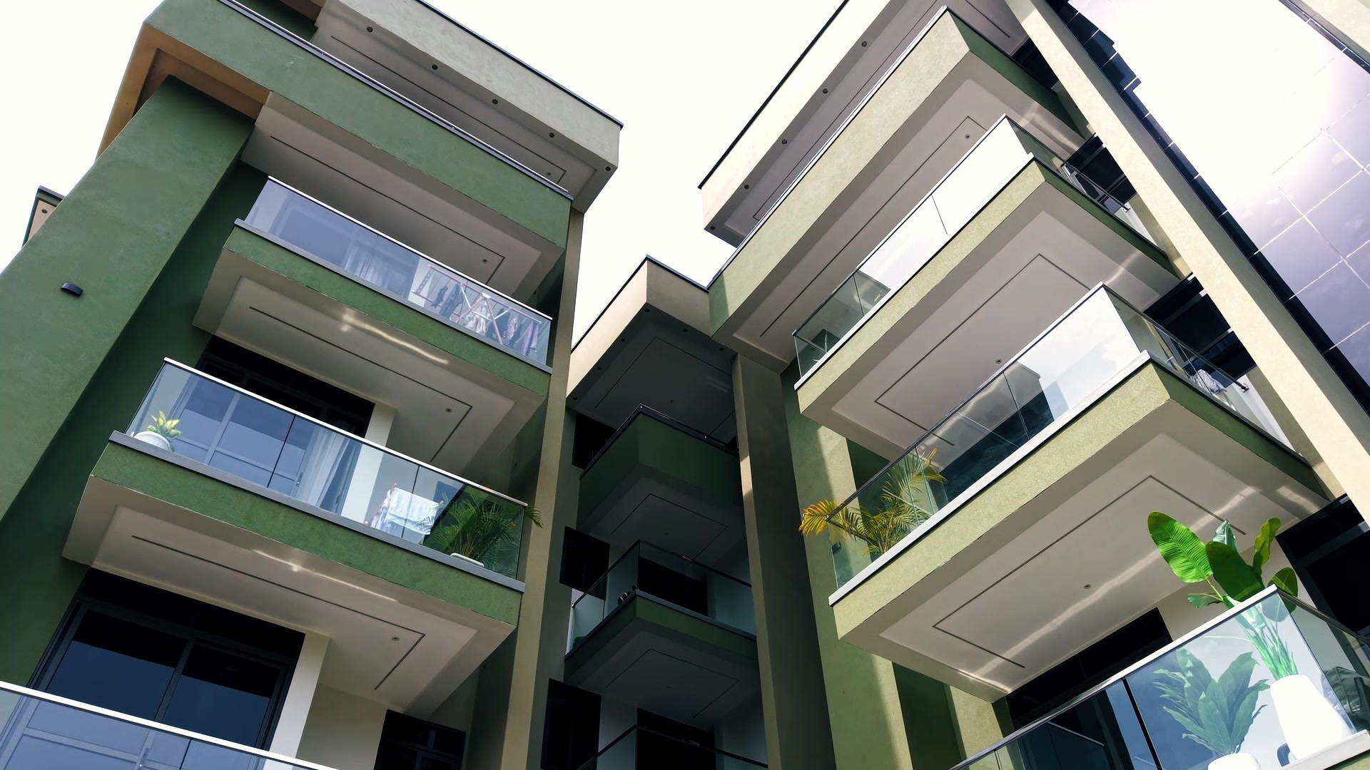 The building's green facade and glass balconies from below