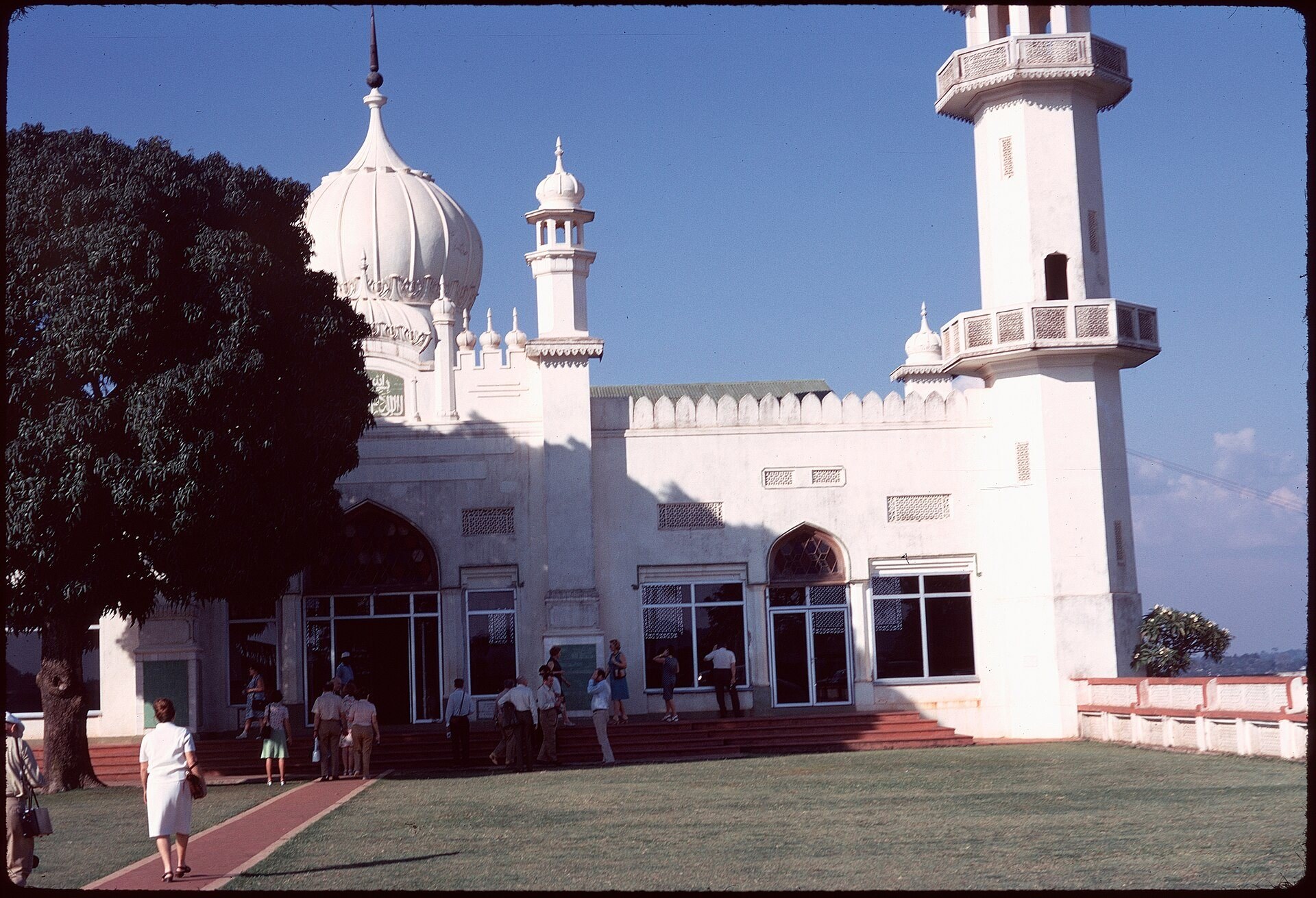 Kibuli Mosque's white domes and minaret in bright sun, with people on the steps, 1971