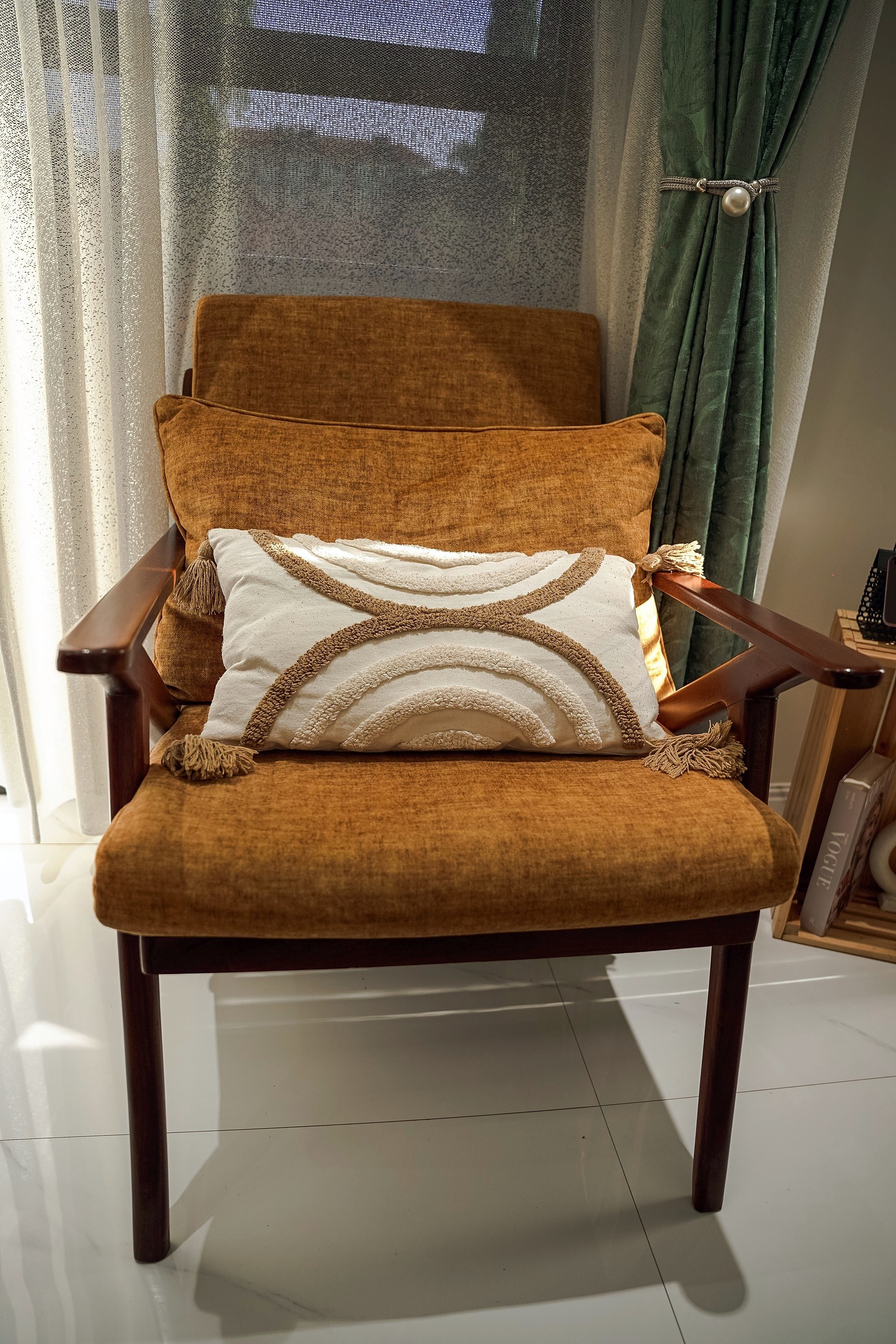 A rust reading chair with a cream cushion by the window